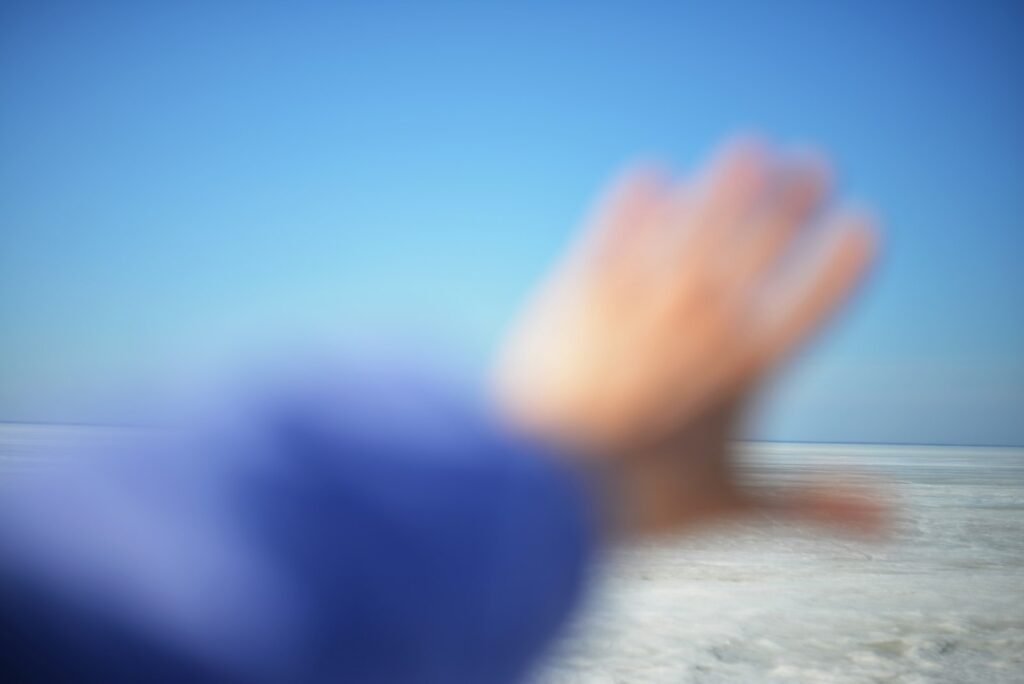 Mano extendida hacia un cielo azul intenso