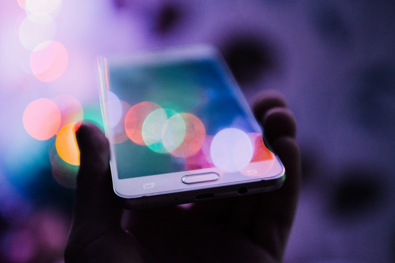 Móvil en la mano mostrando anuncios, afectado por las exclusiones de ubicaciones en Meta Ads