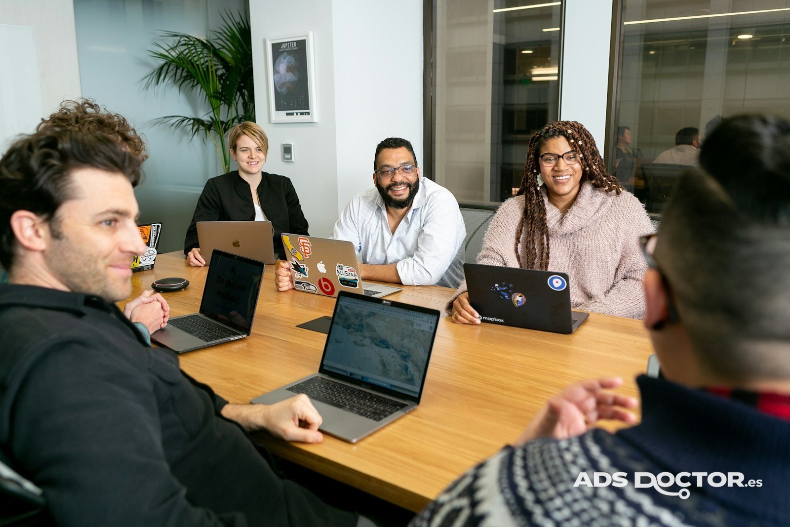 Equipo de una agencia trabajando con portátiles alrededor de una mesa